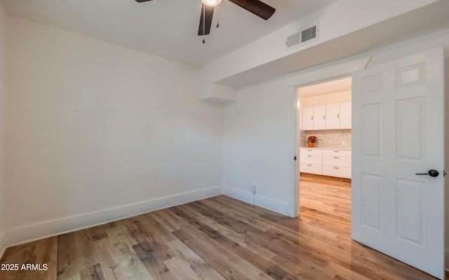 spare room with light wood finished floors, a ceiling fan, and visible vents
