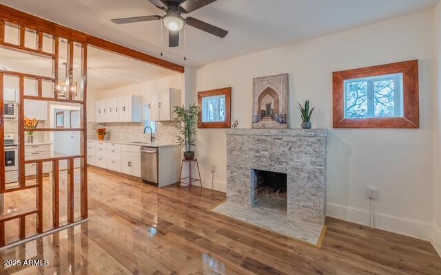 living area featuring baseboards, a ceiling fan, wood finished floors, and a healthy amount of sunlight