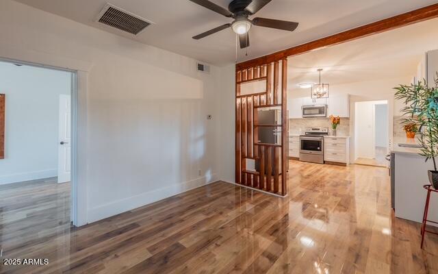 spare room featuring a ceiling fan, visible vents, and light wood-style flooring