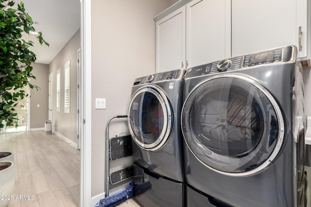 laundry room featuring separate washer and dryer, light hardwood / wood-style flooring, and cabinets