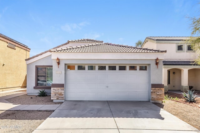 mediterranean / spanish-style house with stone siding, stucco siding, and a garage