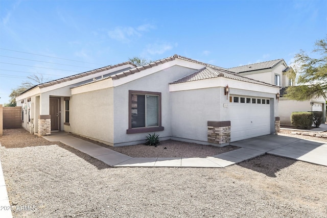 view of side of home featuring an attached garage, a tile roof, stucco siding, stone siding, and driveway