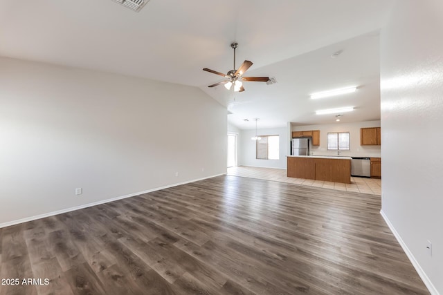 unfurnished living room with visible vents, baseboards, lofted ceiling, ceiling fan with notable chandelier, and wood finished floors