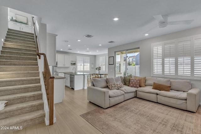 living room with ceiling fan, sink, and light wood-type flooring