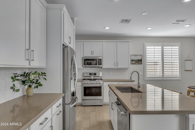 kitchen with tasteful backsplash, appliances with stainless steel finishes, sink, and white cabinets