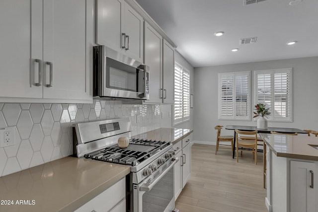 kitchen with white cabinetry, tasteful backsplash, stainless steel appliances, and light hardwood / wood-style flooring