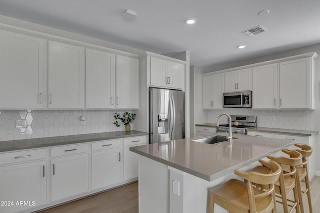 kitchen featuring sink, white cabinetry, a kitchen breakfast bar, stainless steel appliances, and a kitchen island with sink