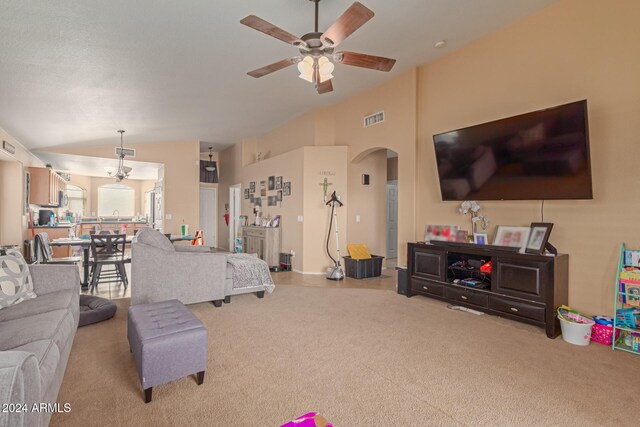 carpeted living room with ceiling fan and vaulted ceiling