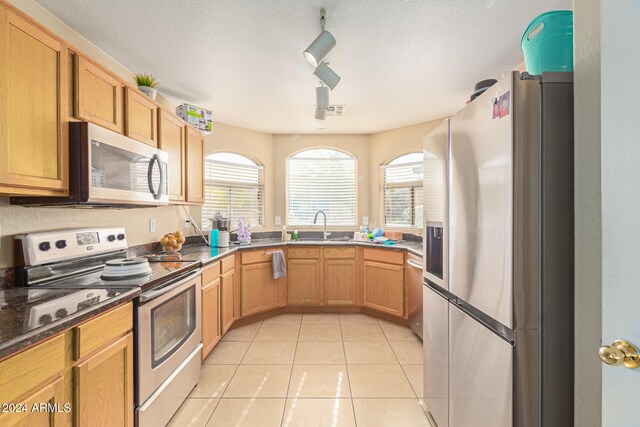 kitchen featuring light tile patterned floors, a textured ceiling, stainless steel appliances, and sink