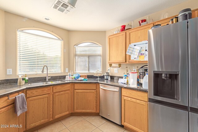 kitchen with dark stone countertops, light tile patterned floors, sink, and appliances with stainless steel finishes