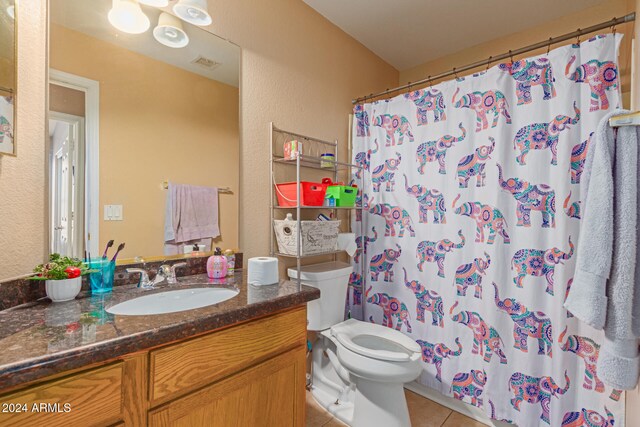 bathroom featuring curtained shower, tile patterned flooring, vanity, and toilet