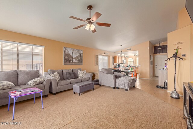 living room featuring ceiling fan with notable chandelier, light tile patterned flooring, and lofted ceiling