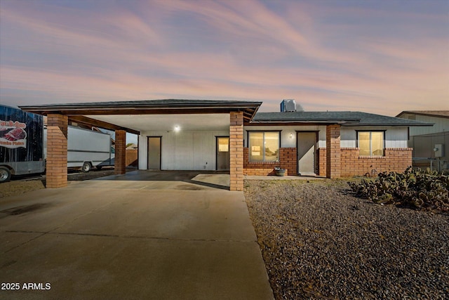 view of front of property with concrete driveway, an attached carport, solar panels, and brick siding