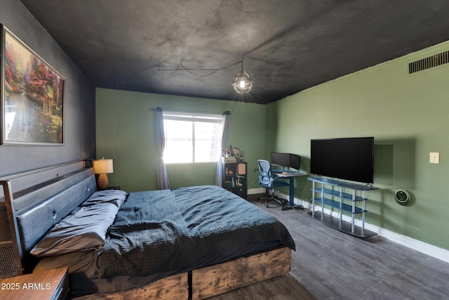 bedroom with visible vents, baseboards, and wood finished floors