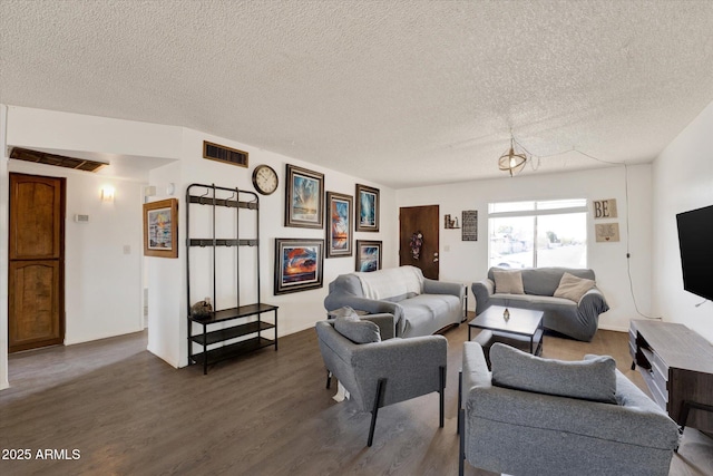 living area with a textured ceiling, wood finished floors, and visible vents