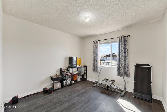 misc room featuring a textured ceiling, baseboards, and dark wood-type flooring