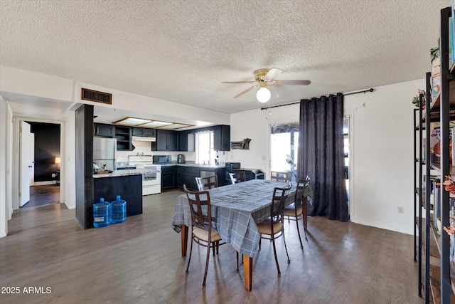 dining space with dark wood-style flooring, visible vents, ceiling fan, and a textured ceiling