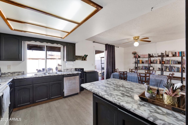 kitchen featuring a sink, light stone countertops, plenty of natural light, and stainless steel dishwasher