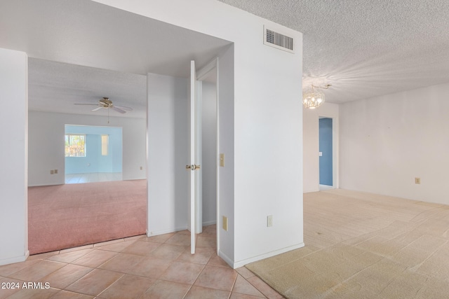 carpeted spare room with ceiling fan with notable chandelier and a textured ceiling