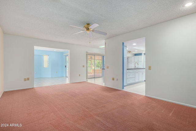 carpeted empty room with a textured ceiling, ceiling fan, and sink