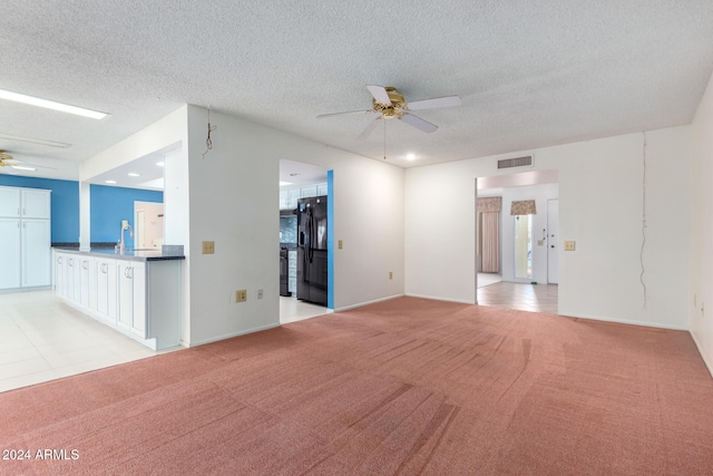 unfurnished living room featuring a textured ceiling, ceiling fan, and light carpet