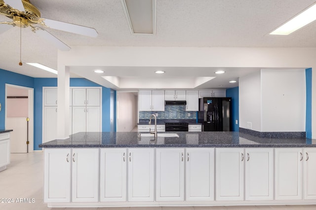 kitchen featuring sink, a raised ceiling, dark stone countertops, white cabinets, and black appliances