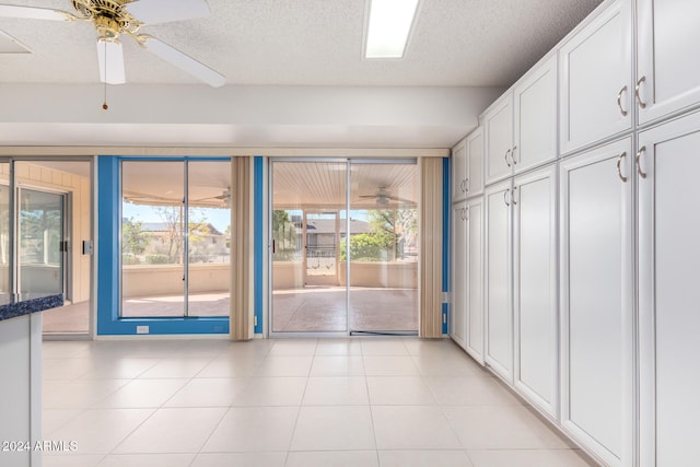 tiled empty room featuring a textured ceiling, ceiling fan, and a healthy amount of sunlight