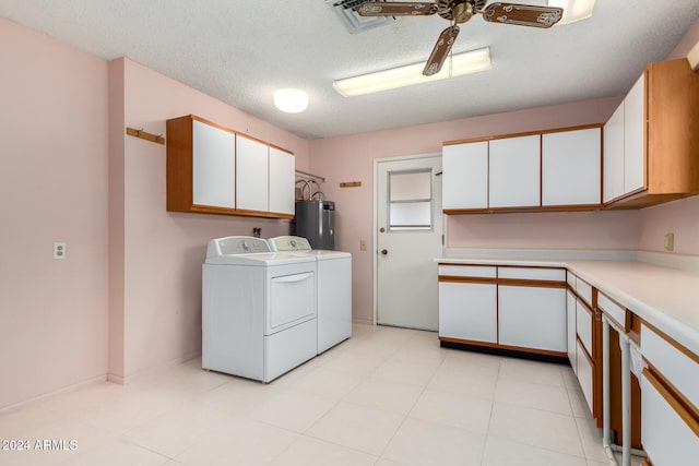 laundry area with cabinets, a textured ceiling, electric water heater, ceiling fan, and washing machine and clothes dryer