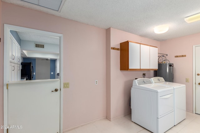 laundry area with cabinets, separate washer and dryer, water heater, a textured ceiling, and light tile patterned floors