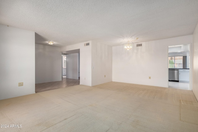 carpeted empty room featuring a textured ceiling and a notable chandelier