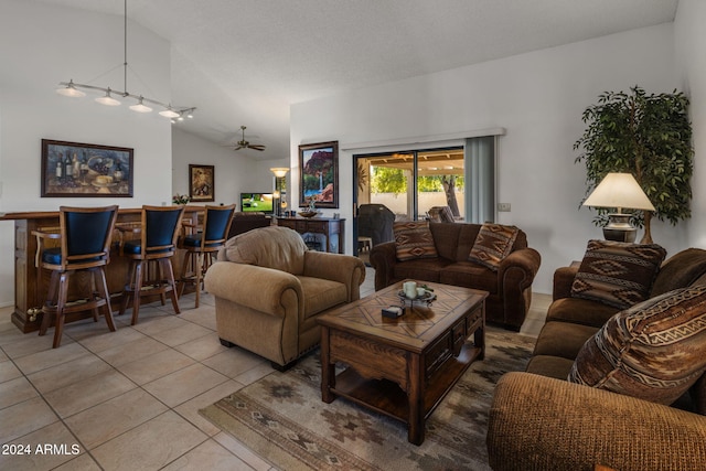 tiled living room featuring a bar, ceiling fan, and vaulted ceiling
