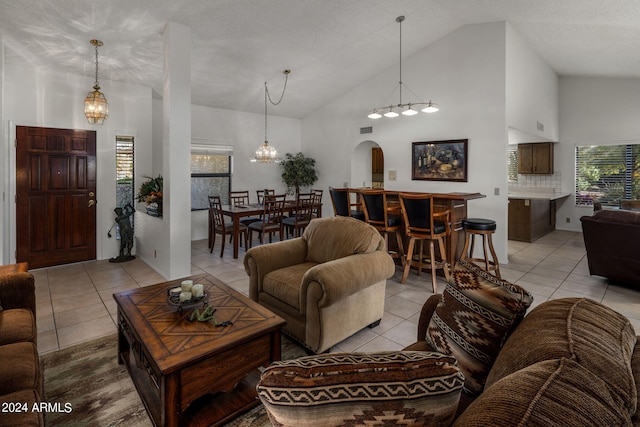 living area featuring light tile patterned floors, visible vents, arched walkways, an inviting chandelier, and high vaulted ceiling