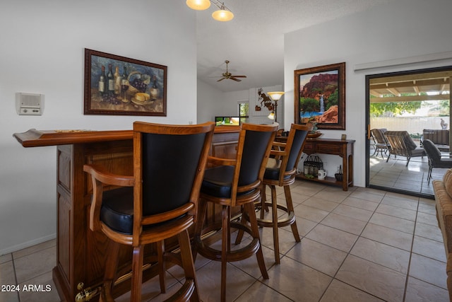bar featuring baseboards, vaulted ceiling, tile patterned flooring, a ceiling fan, and a dry bar