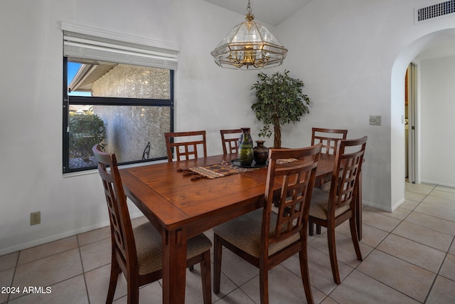 dining space with an inviting chandelier, arched walkways, visible vents, light tile patterned flooring, and baseboards