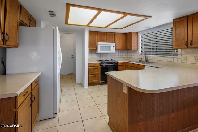 kitchen with tasteful backsplash, a sink, light countertops, white appliances, and a peninsula