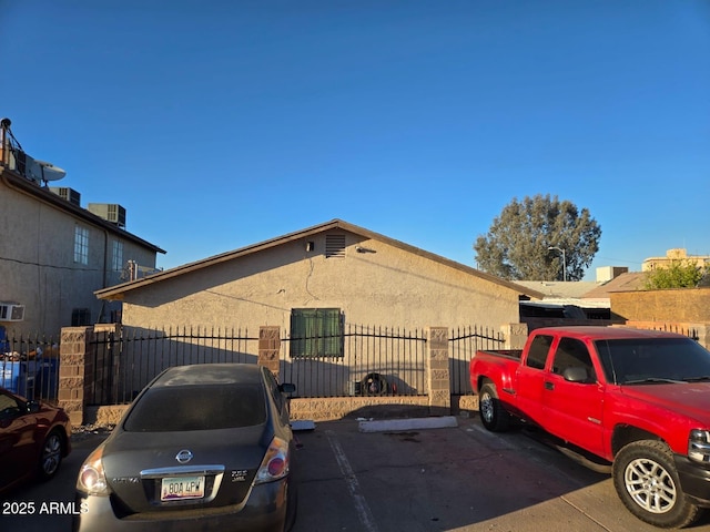 view of front of property with uncovered parking, fence, and stucco siding