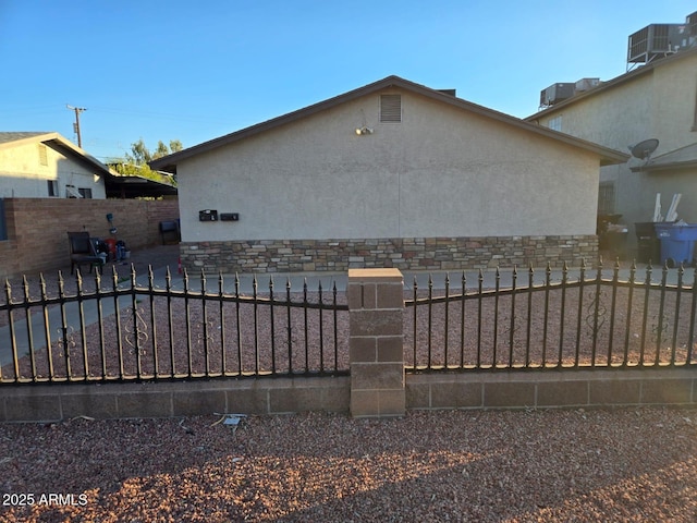 exterior space featuring a fenced front yard and central AC