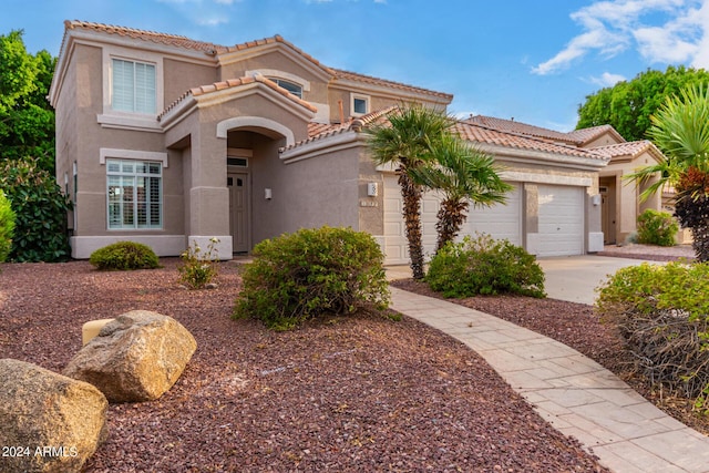 mediterranean / spanish house featuring a tile roof, stucco siding, a garage, and concrete driveway