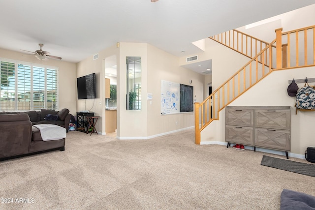 carpeted living room with stairway, ceiling fan, and baseboards