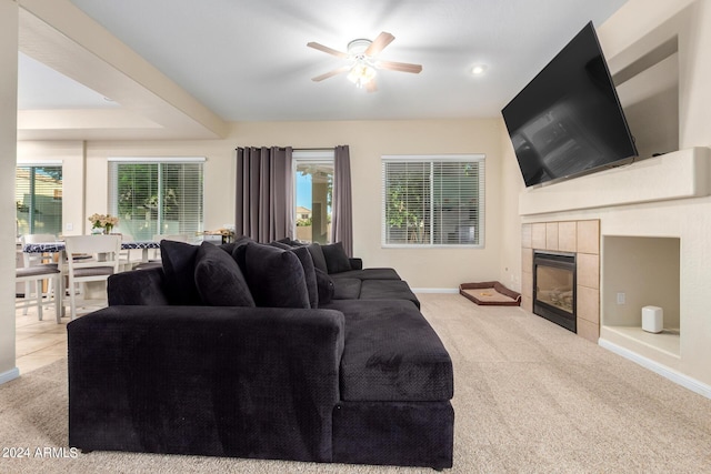 living room with carpet floors, a ceiling fan, baseboards, and a tile fireplace