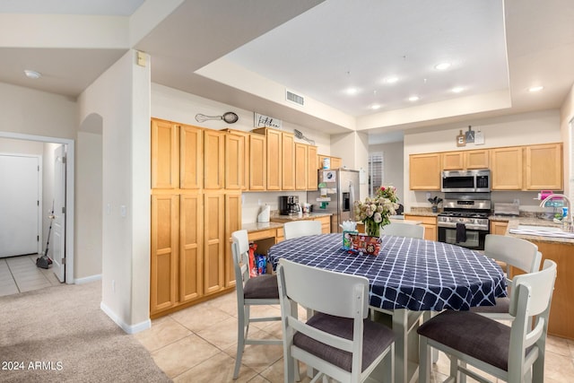 dining space with light tile patterned flooring, a tray ceiling, baseboards, light carpet, and recessed lighting