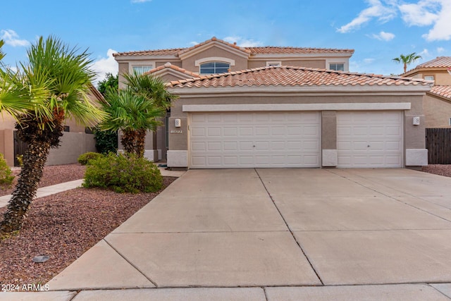 mediterranean / spanish house featuring a garage, driveway, stucco siding, and fence