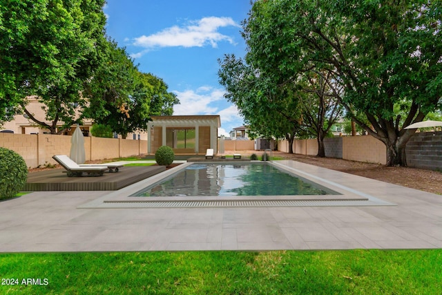 view of swimming pool featuring a fenced backyard, a patio, an exterior structure, and an outbuilding