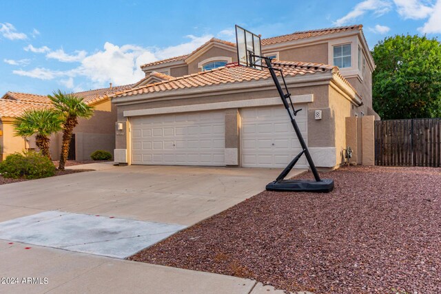 mediterranean / spanish home featuring concrete driveway, a garage, fence, stucco siding, and a tiled roof