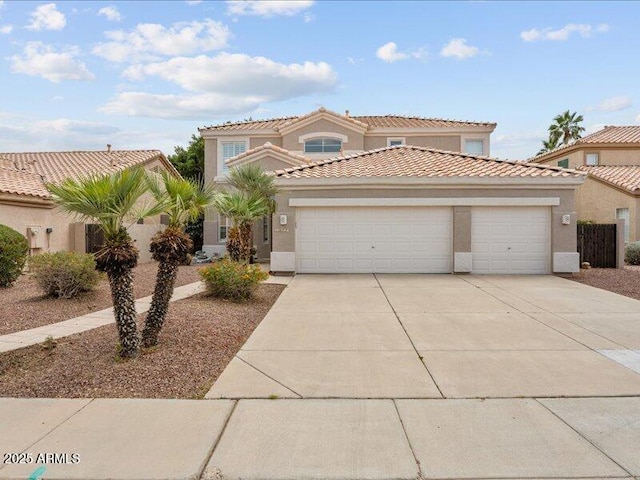 mediterranean / spanish house featuring a garage, driveway, stucco siding, and a tile roof