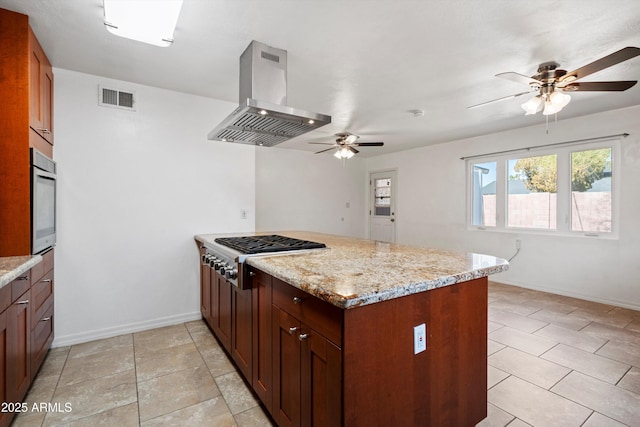 kitchen with wall oven, light stone counters, island exhaust hood, kitchen peninsula, and stainless steel gas stovetop