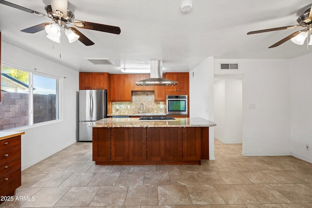 kitchen with light stone counters, island range hood, stainless steel appliances, and sink