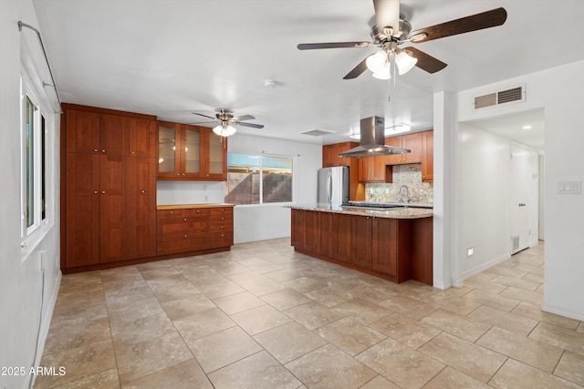 kitchen with stainless steel refrigerator, sink, decorative backsplash, island exhaust hood, and ceiling fan