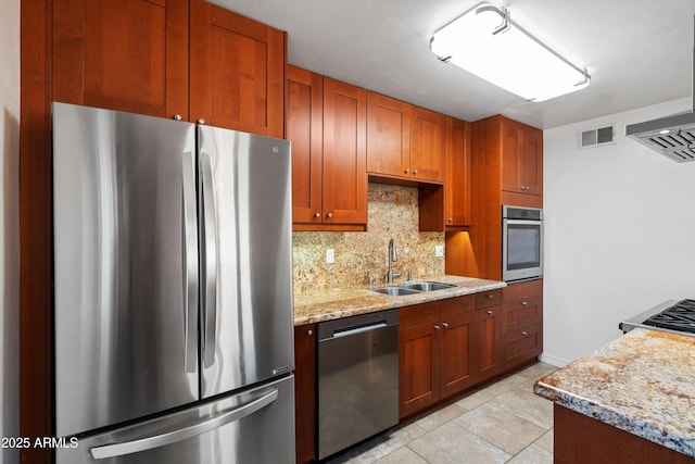 kitchen featuring sink, light stone counters, tasteful backsplash, light tile patterned floors, and appliances with stainless steel finishes