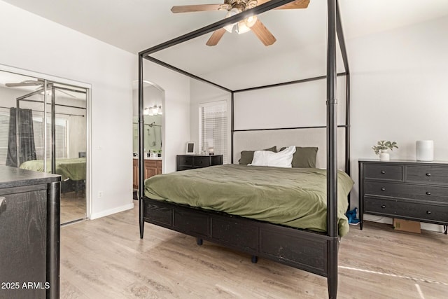 bedroom with baseboards, a ceiling fan, ensuite bath, and wood finished floors
